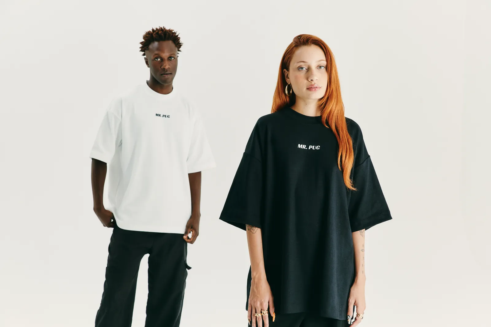 Casal de modelos vestindo camiseta premium MR PUG · branca e preta · produção MAISON CARIOCA
