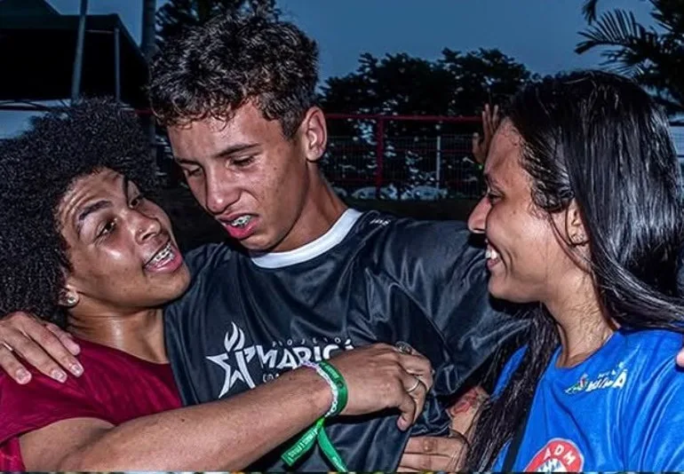 Atleta e organizador se abraçando na pista, os dois com a camisa do evento